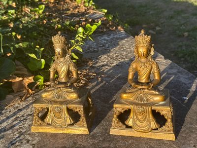 two statues of buddhas sitting on a table
