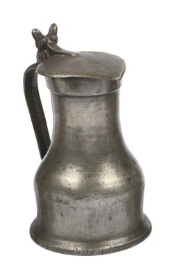 an antique silver pitcher with a bird on the handle