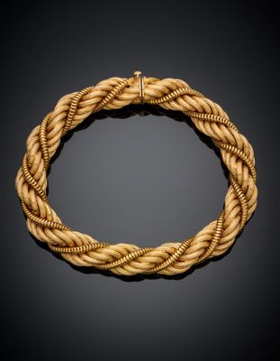 a gold rope bracelet with a clasp on a black background