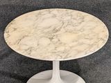 a white marble table with a circular base on a grey carpet