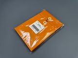 une enveloppe orange sur laquelle est accrochée une étiquette, posée sur une table
