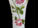 un vase blanc orné de fleurs roses sur fond noir