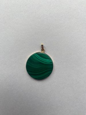 un pendentif en pierre verte muni d'une bélière plaquée or