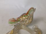 a glass bird that is sitting on a branch