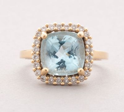 a close up of a ring with a blue topaz stone surrounded by diamonds