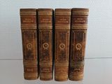 Quatre vieux livres sont alignés sur une table en verre