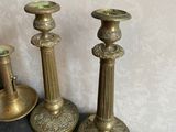three brass candlesticks sitting on a table next to a vase