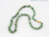 collier composé de perles de jade vert avec un fermoir en or, sur fond blanc