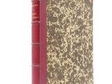 an old book with a red cover sitting on top of a white surface