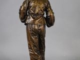 bronze statue of a man with a hat and jacket on a base