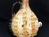 un vase en verre muni d'une anse, sur fond noir