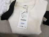 a white sweater with a black tie and a tag on it