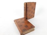 an old book with a brown cover sitting on top of a white surface