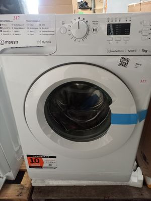une machine à laver blanche posée sur des palettes à côté d'une pile de cartons