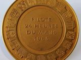 une image représentant une plaque en or sur laquelle sont inscrits les mots « pilote 24 heures du Mans »