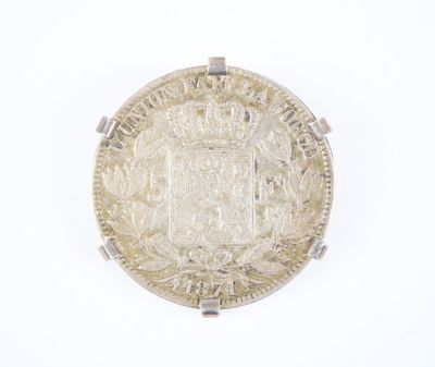 une vieille pièce d'argent posée sur une surface blanche, sur laquelle figure une couronne