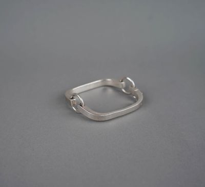 un gros plan d'une bague en argent posée sur une surface grise