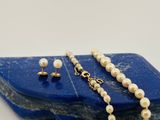 ensemble collier et boucles d'oreilles avec des perles sur une pierre bleue