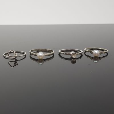 cinq bagues différentes ornées de perles et de diamants sur un fond noir