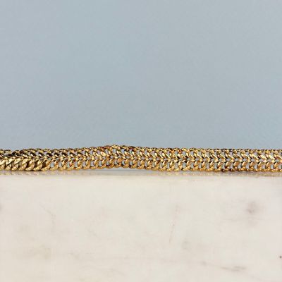 un gros plan d'un bracelet à chaîne en or posé sur une surface en marbre