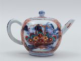 an oriental teapot with a basket of flowers on it