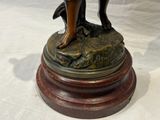 une statue en bronze représentant une femme et un chien, posée sur un socle