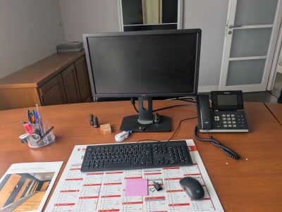 a desk with a computer, keyboard, phone, and calendar on it
