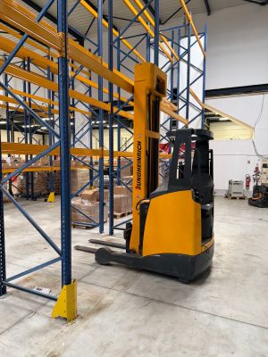 a forklift in a large warehouse with lots of pallets