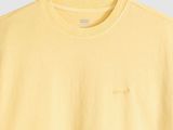 a yellow t shirt with a small embroidered logo on the chest