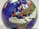 une boule de verre posée sur un socle, sur une surface blanche