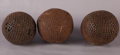 Trois boules en bois sont posées les unes à côté des autres sur une surface blanche