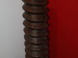 a tall metal object sitting on the floor in front of a red wall