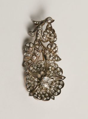 Une broche ancienne sertie de diamants est posée sur une surface blanche