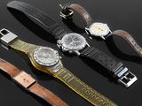 three different watches are sitting on a black surface with a black background