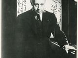 photographie en noir et blanc d'un homme en costume et cravate jouant du piano