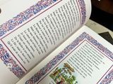 a person holding a book open on a table