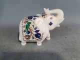 un éléphant blanc avec un motif bleu et vert sur le dos