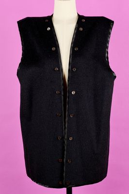 un gilet noir posé sur un mannequin, devant un fond rose