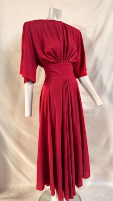 a red dress on a mannequin stand against a white backdrop