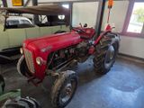 a red tractor parked in a garage next to a green car