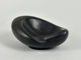 a black bowl shaped like a chair on a white surface