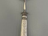 a silver spoon with a handle that has a design on it