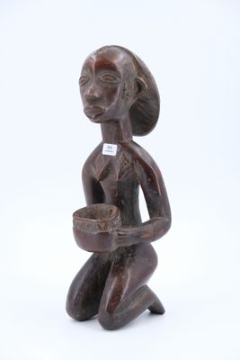 une vieille figurine en bois représentant une femme tenant un bol