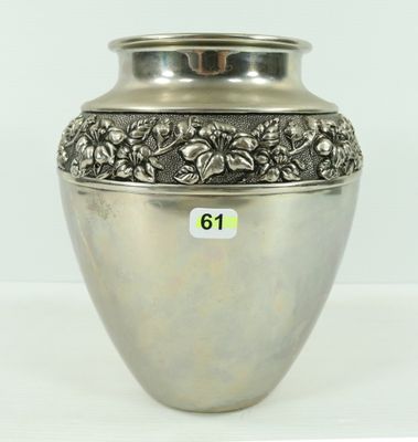 a silver vase with flowers on it sitting on a table