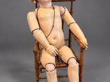an old wooden doll sitting in a wooden chair with red shoes