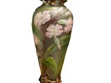un vase avec des fleurs peintes dessus, posé sur une table
