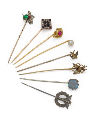 a group of various metal and glass brooches and pins