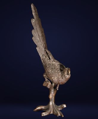 une sculpture en bronze représentant un oiseau perché sur une branche