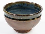a brown and blue bowl sitting on a white surface