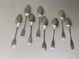 six cuillères en argent sont alignées sur une table